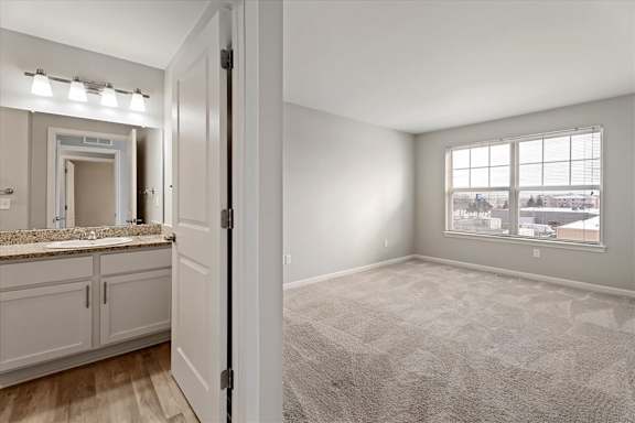 A carpeted room with a window and a bathroom visible through the door.