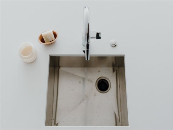 a sink with a faucet and soap on the side of it
