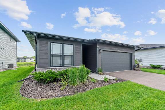 A modern house with a grey exterior and a landscaped front yard.