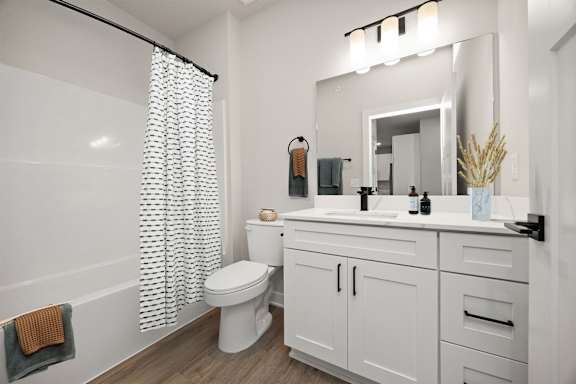 A white bathroom with a toilet, sink, and shower curtain.
