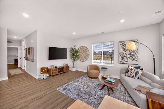 A living room with a grey couch, a wooden coffee table, and a large window.