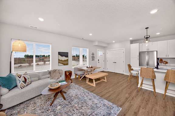 A modern living room with a grey sofa, wooden coffee table, and a kitchen area in the background.
