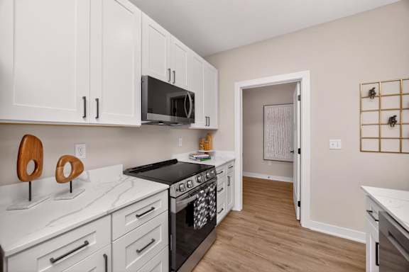 A kitchen with white cabinets and a black stove top.