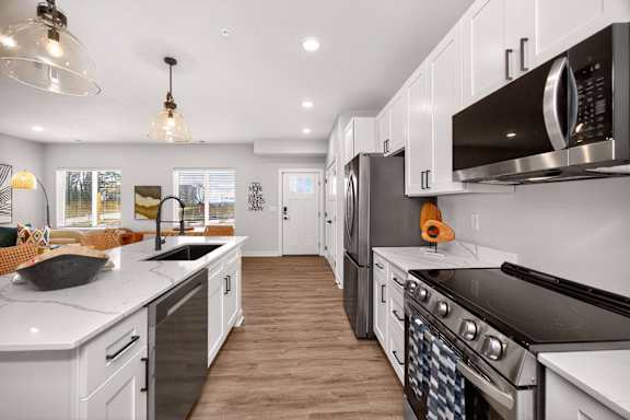A modern kitchen with white cabinets and black appliances.
