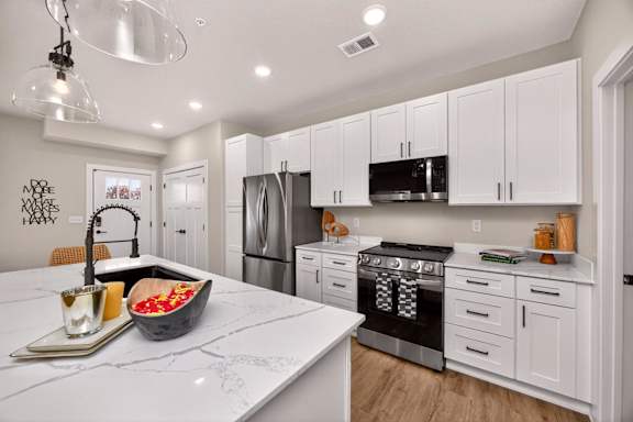 A modern kitchen with white cabinets and a marble countertop.