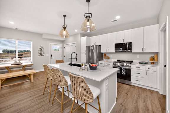 A kitchen with a white island and wooden chairs.