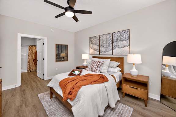 A bedroom with a bed, nightstands, and a ceiling fan.