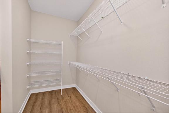 Empty walk-in closet with shelves and a wooden floor.