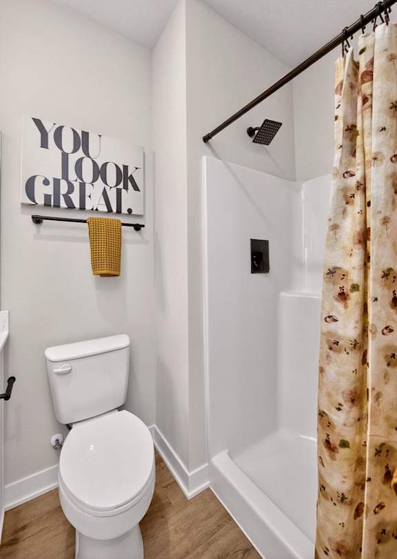 A white toilet sits under a You Look Great sign in a small bathroom.
