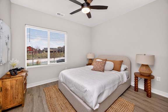 A bedroom with a bed, a ceiling fan, and a window with blinds.