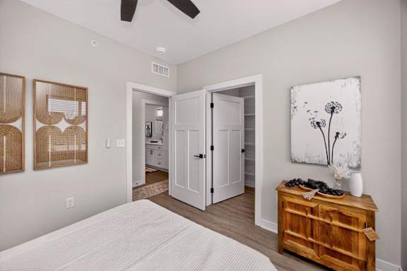 A bedroom with a bed, a dresser, and a painting on the wall.