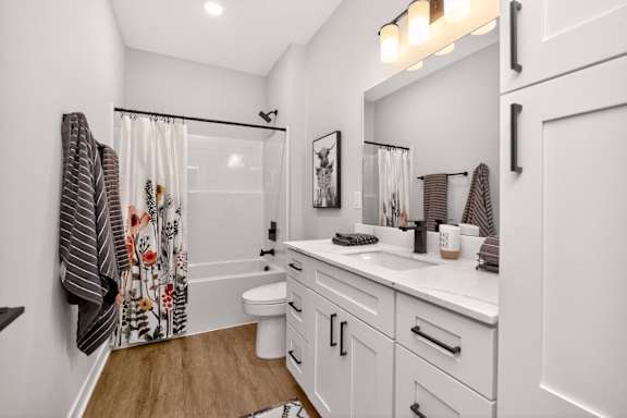 A white bathroom with a wooden floor and a white toilet.