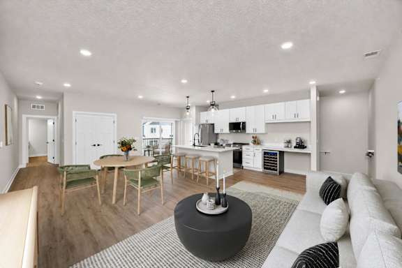 A modern living room with a kitchen in the background.