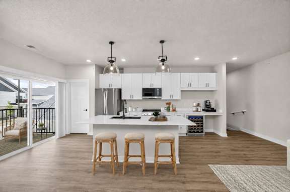 A kitchen with a white countertop and wooden bar stools.