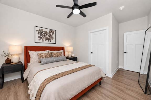 A bedroom with a bed, nightstands, and a ceiling fan.