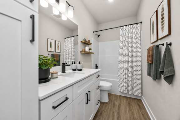 A white bathroom with a toilet, sink, and shower.