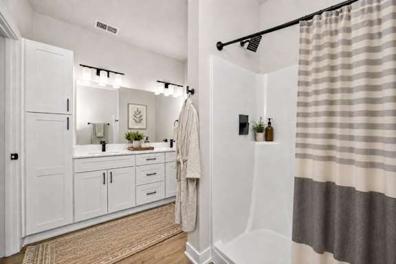 A bathroom with a white cabinet, a sink, a mirror, a towel, and a shower curtain.