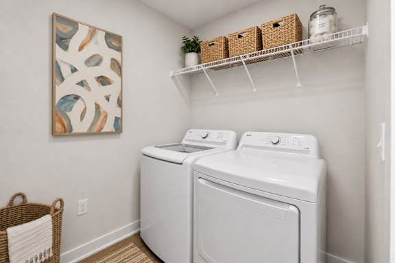 A laundry room with a washer and dryer and a basket on the floor.