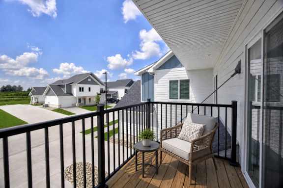 A balcony with a chair and a potted plant overlooks a residential area.
