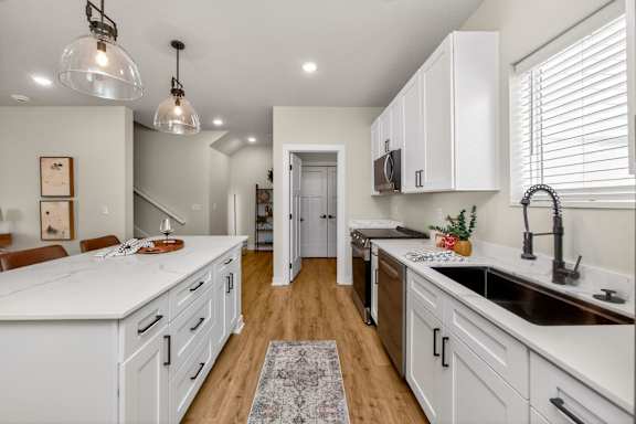 A kitchen with white cabinets and a rug on the floor.