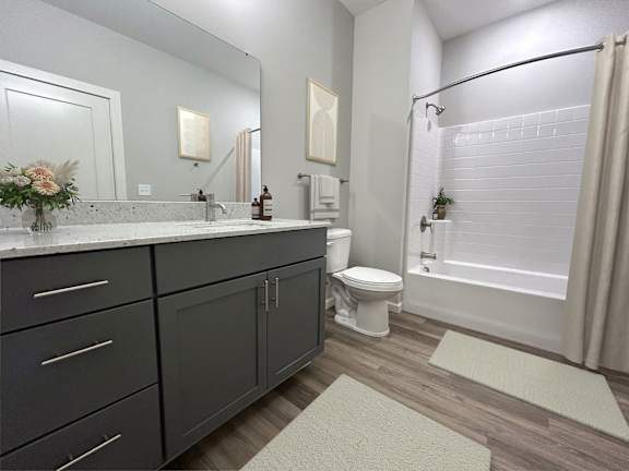 A bathroom with a toilet, sink, and mirror.