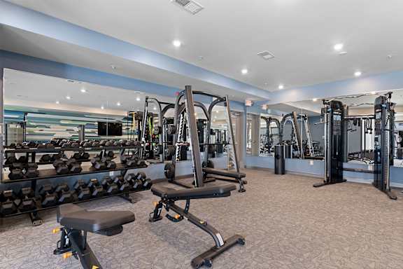 A gym with a variety of equipment including treadmills, weights, and exercise machines.