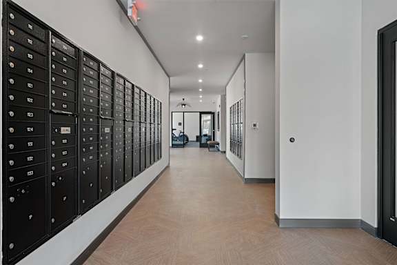 A long hallway with black mailboxes on the wall.