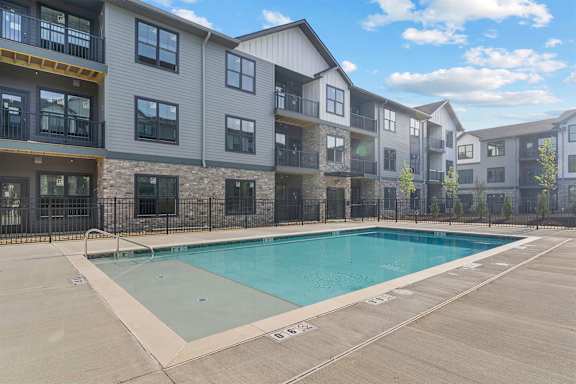 A swimming pool is surrounded by apartment buildings.