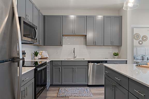 A kitchen with grey cabinets and a white countertop.