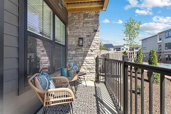 A patio with a wicker chair and a stone pillar.