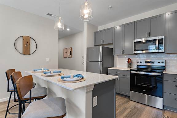 A kitchen with a white countertop and grey cabinets.