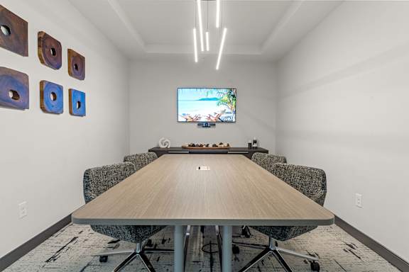 A conference room with a long table and chairs, a television on the wall, and decorative pieces on the wall.