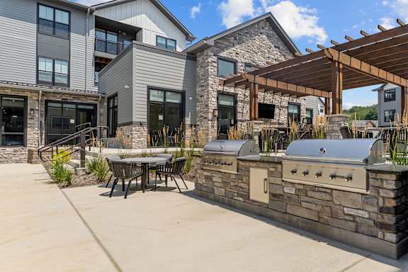 A modern house with a stone wall and a wooden pergola.