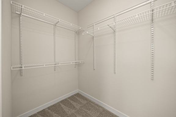 A room with white walls and a carpeted floor with three white shelves on the wall.