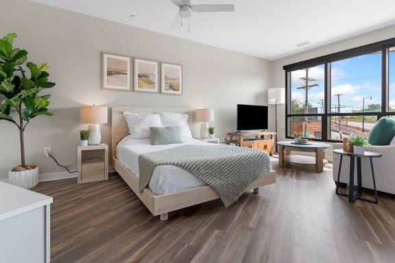 a bedroom with a bed and a tv in a room with hardwood floors