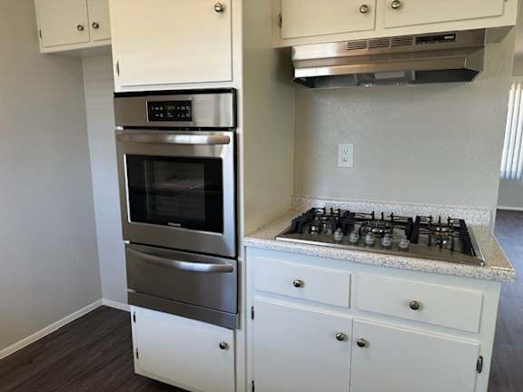 A kitchen with a stainless steel oven and a white cabinet.