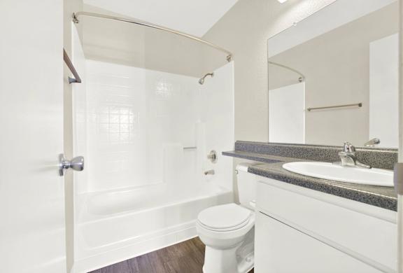 A white toilet sits next to a bathtub in a bathroom.