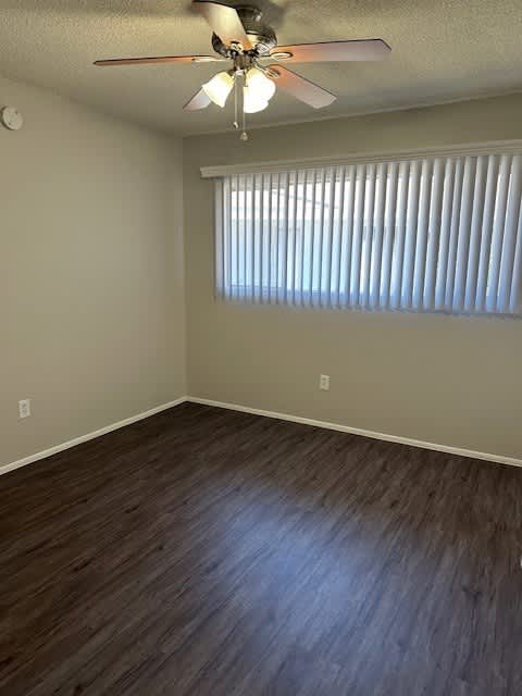 A room with a ceiling fan and wooden flooring.