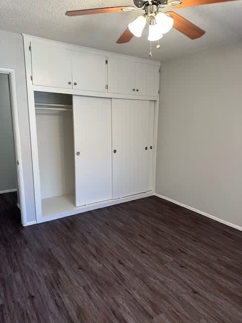 A room with a ceiling fan and built-in cabinets.