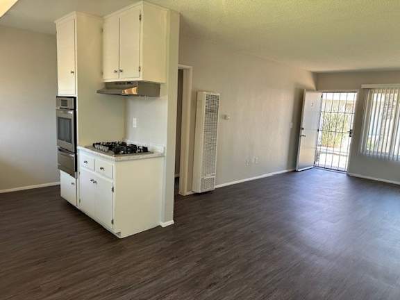 A kitchen with white cabinets and a stove top oven.