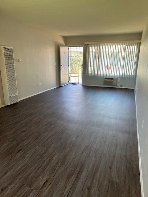 A room with wooden flooring and a sliding glass door.