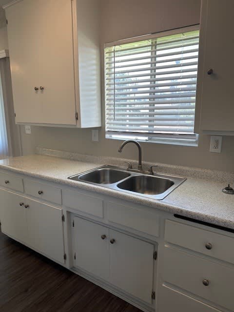 A kitchen with white cabinets and a granite countertop.