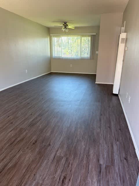 A room with wooden flooring and a window with blinds.