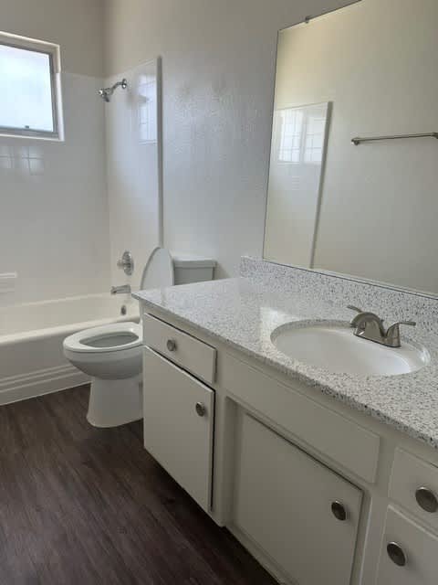 A white bathroom with a toilet, sink, and mirror.
