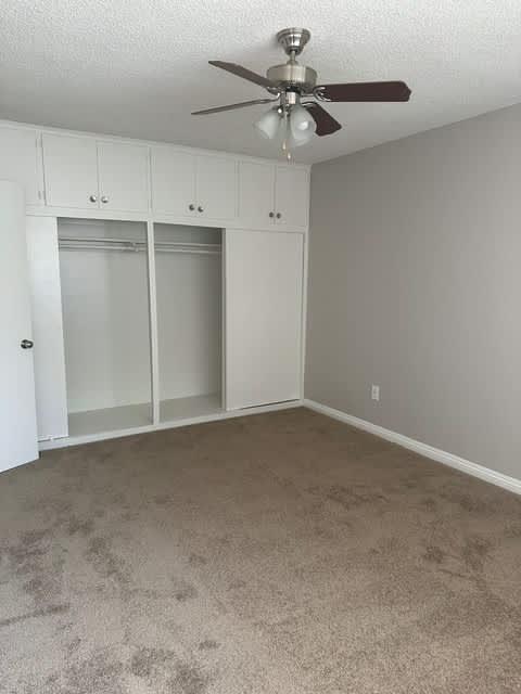 A room with a ceiling fan and carpeted floor.