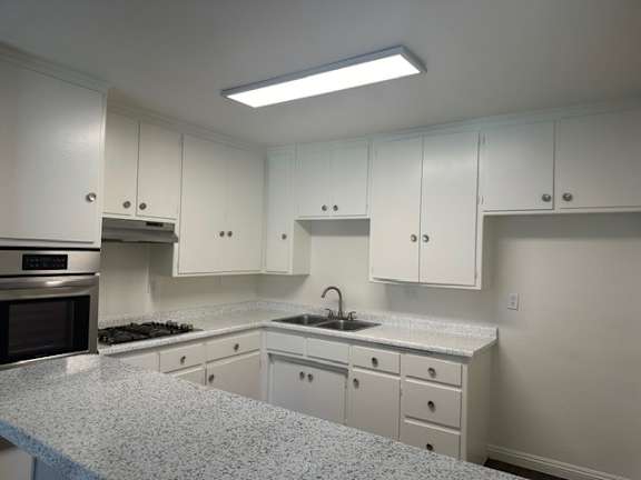 A kitchen with white cabinets and a granite countertop.