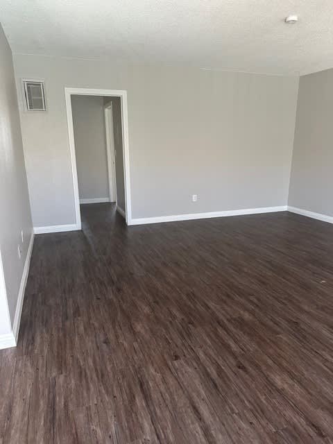 A room with wood flooring and a doorway leading to another room.