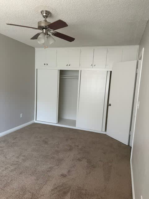 A room with a ceiling fan and a white cabinet.