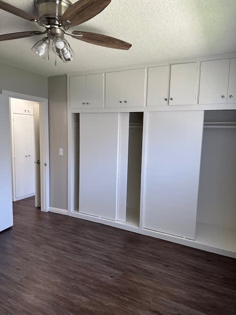 an empty room with white cabinets and a ceiling fan