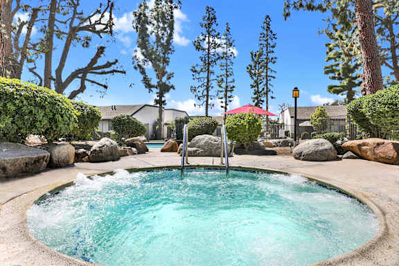A hot tub in the middle of a garden with rocks around it at THE STREAMS Apartments, Apartments, Fullerton, CA